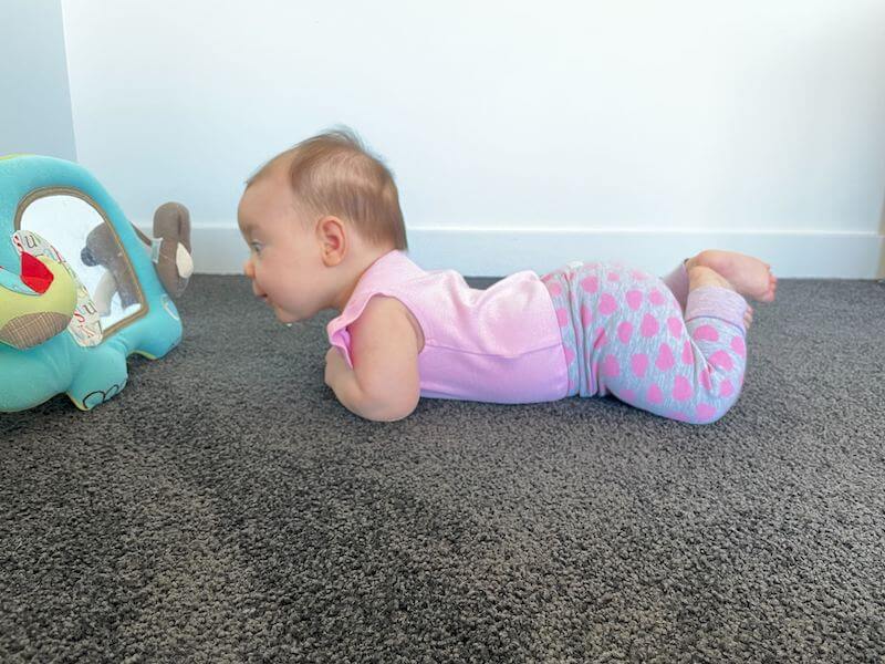 baby lying on tummy to play with soft mirror