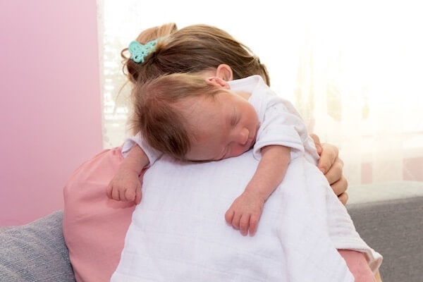 Mother holding her baby upright on her shoulder after feeding