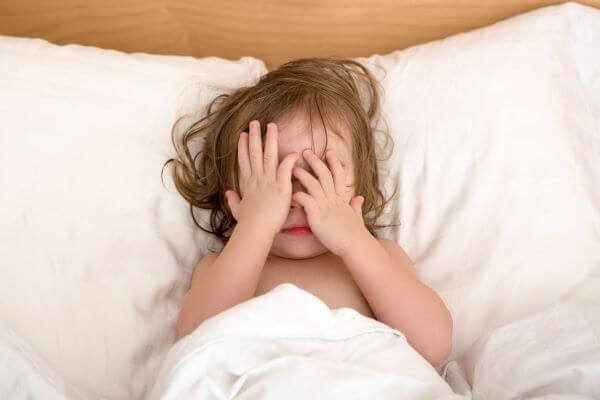 two year old lying in bed refusing to go to sleep
