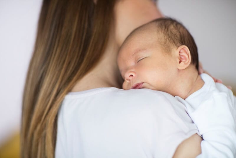 young baby asleep on his mothers shoulder after being rocked to sleep