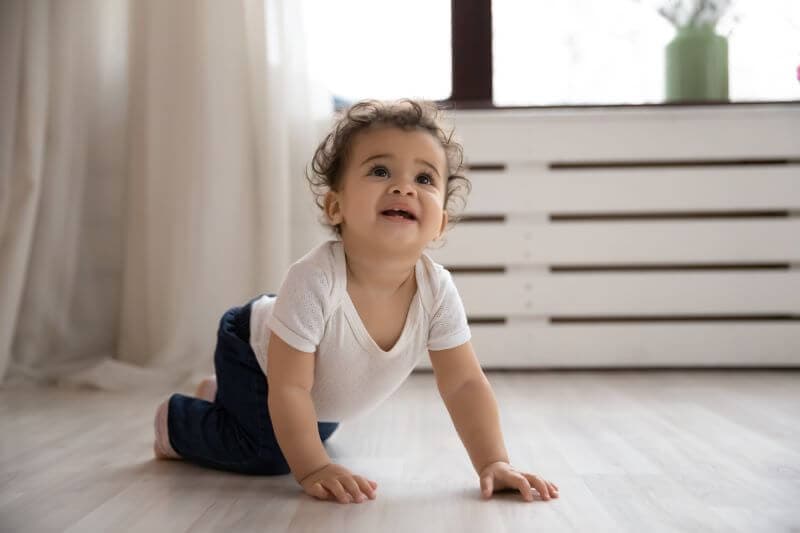 African american baby girl crawling on a timber floor. Shows a baby who has recently learned to crawl